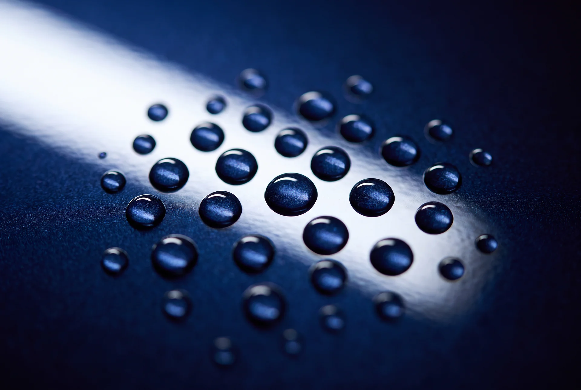 Tight round water beads standing on a freshly coated deep blue panel